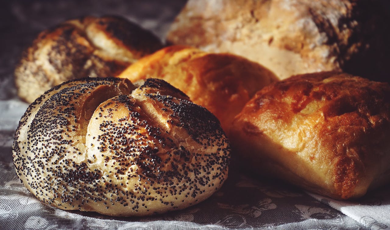 Captivating closeup of freshly baked bread with poppy seeds and buns. Perfect for baked goods enthusiasts.