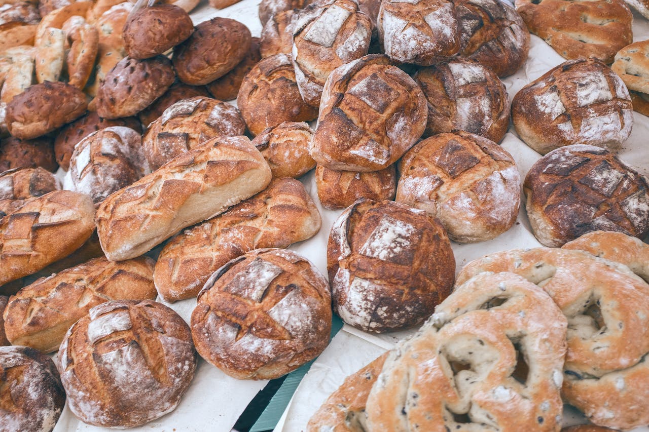 A variety of freshly baked artisan breads displayed on a market stall, showcasing different shapes and textures.
